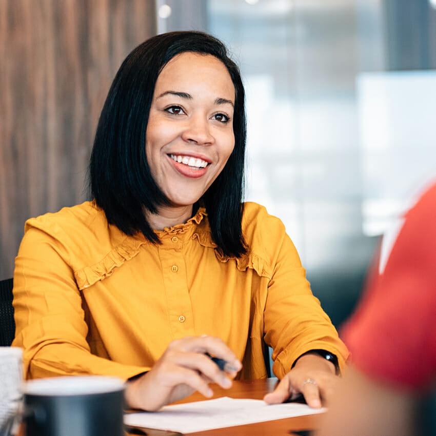 woman smiling at table with a pen and paper