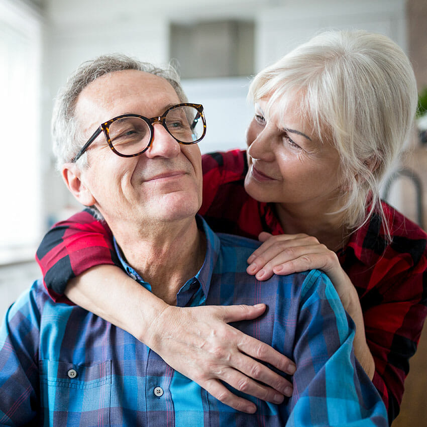 older man and woman smiling while in an embrace