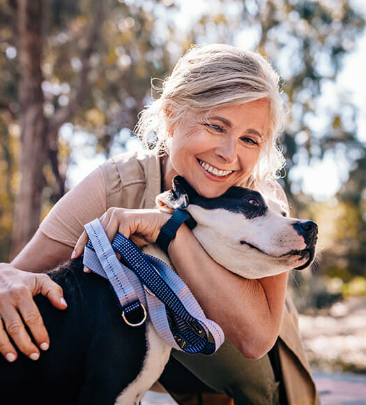 woman smiling while petting a black and white dog