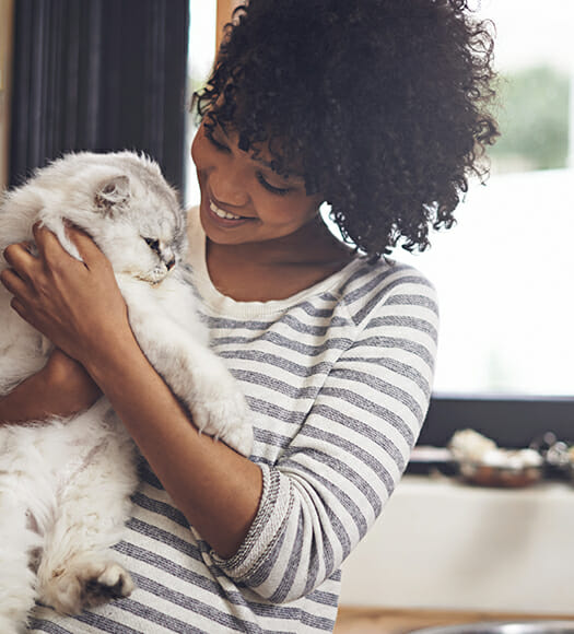 young woman smiling while petting a cat