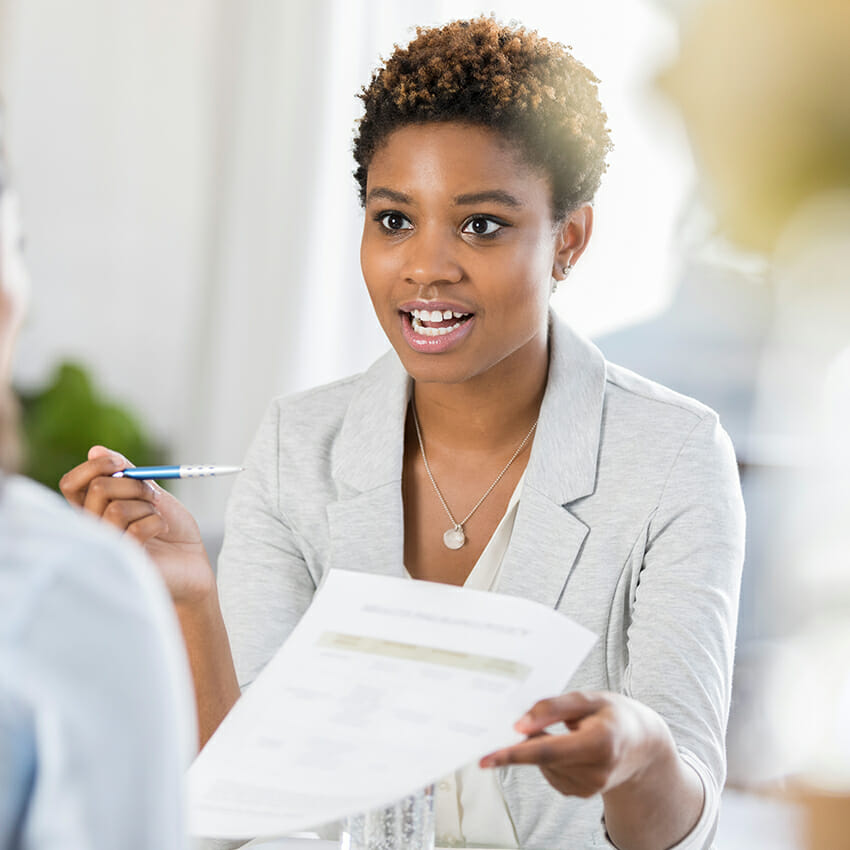 young woman in conversation while holding a pen and paper